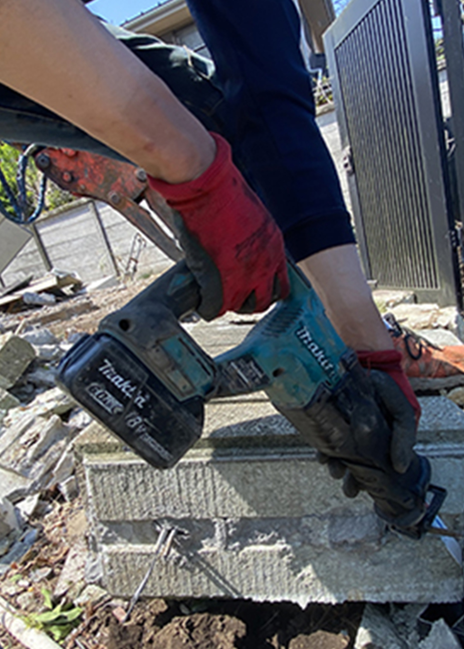 屋外でブロックを電動工具で切断する作業員