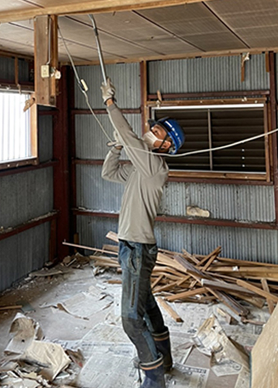室内天井の配線を撤去する作業員
