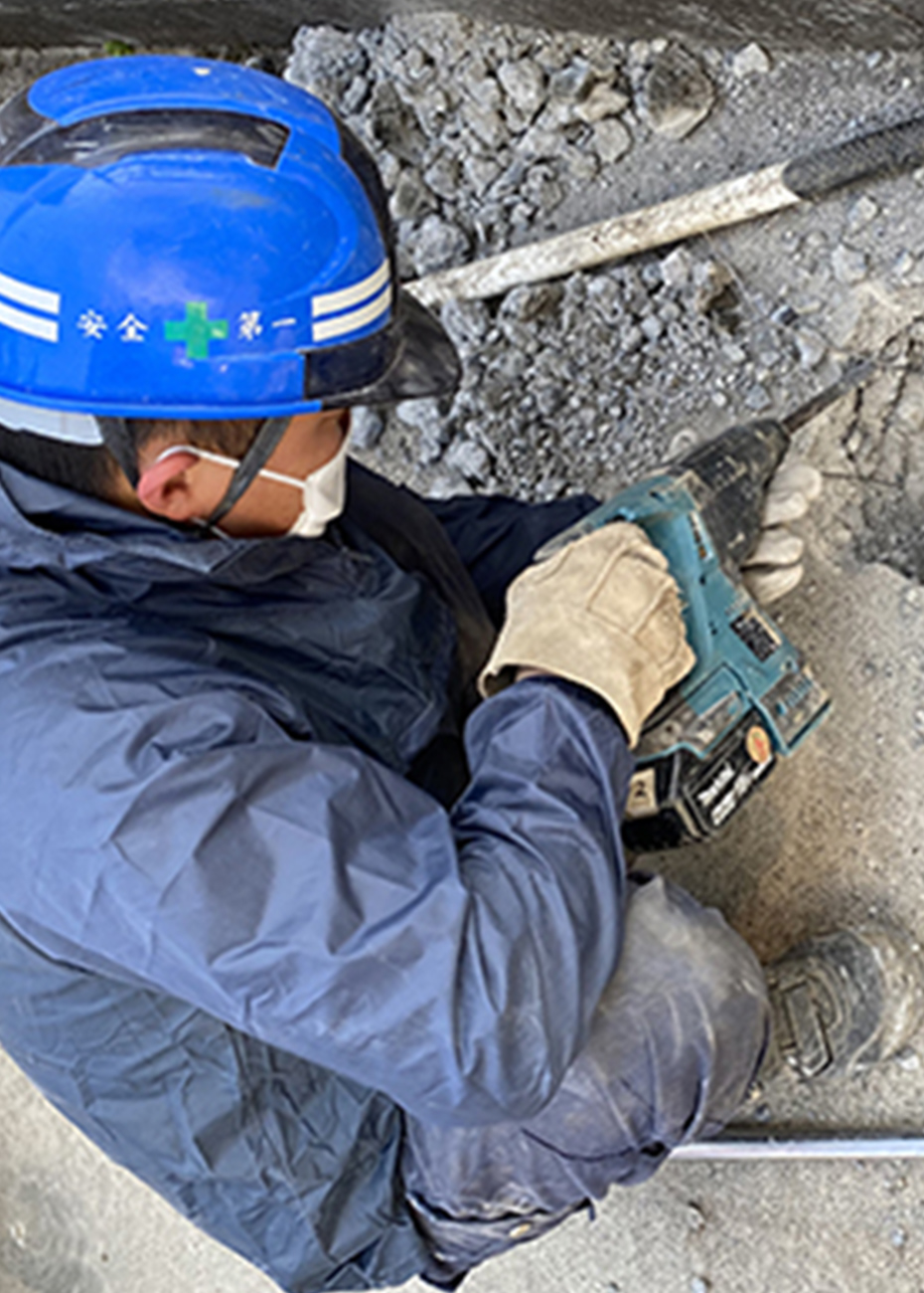 床面でハンマードリルを扱う作業員